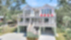 Elevated white house with multiple balconies and red chairs
