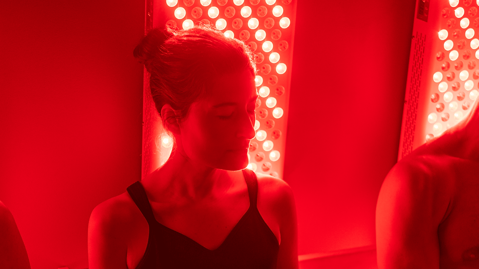 Woman in black top, eyes closed, sits near glowing red light panels, creating a calming and ambient atmosphere.