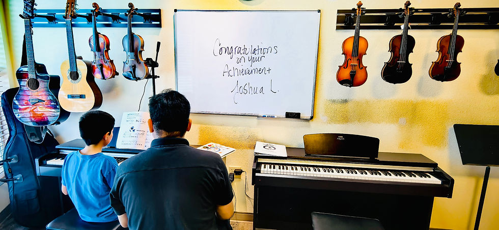 Man and boy at a piano in a music classroom, with guitars on the walls and a whiteboard reading Congratulations on your achievement Joshua L.