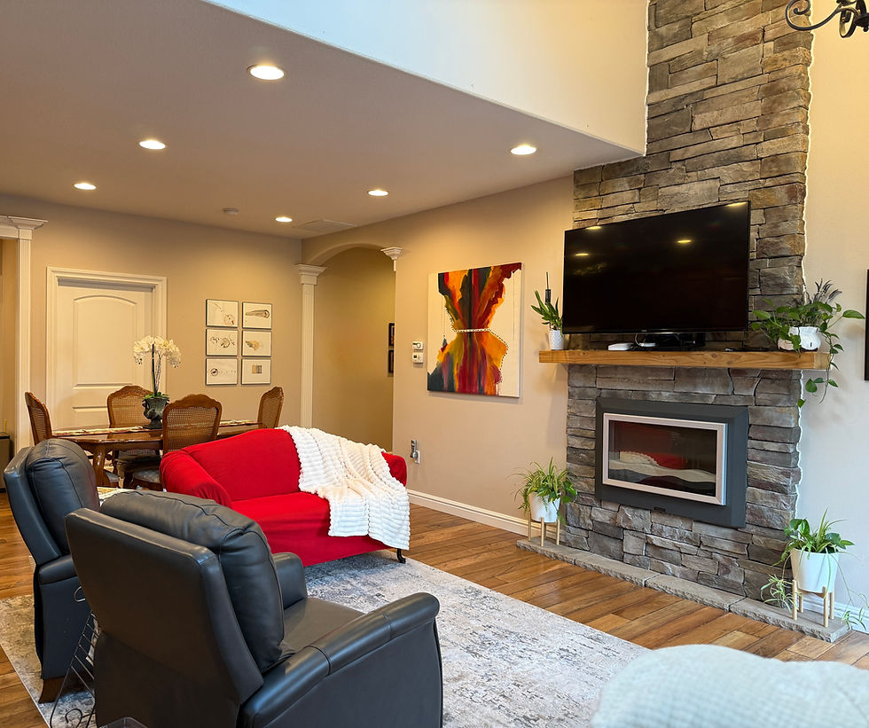 Spacious living room with stone fireplace and TV at Vineyard Home Senior Living
