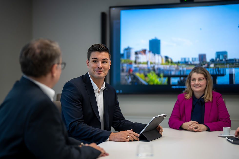 Marco Reimann mit Tablet am Konferenztisch, im Hintergrund Düsseldorfer Skyline auf einem Bildschirm