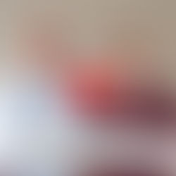 Elektrofahrzeug beim Laden an einer Stromtankstelle mit orangefarbenem Kabel, im Hintergrund ein Schild für den Ladeplatz.