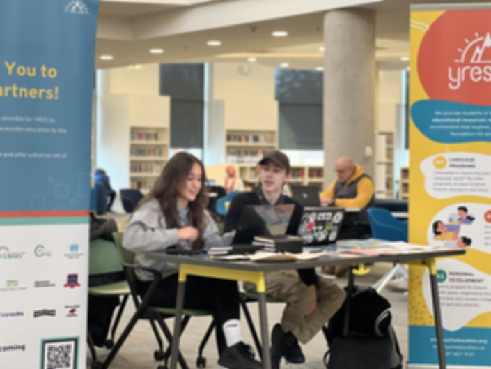 Volunteer event staffers facilitating the YRES booth at a library