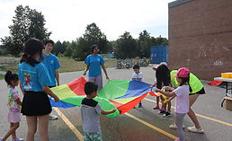 YRES staff and campers playing with parachute in schoolyard
