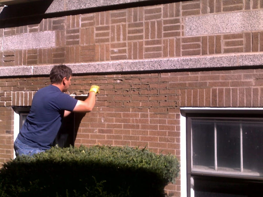 AB Masonry specialist repairing damaged brickwork on a home exterior.
