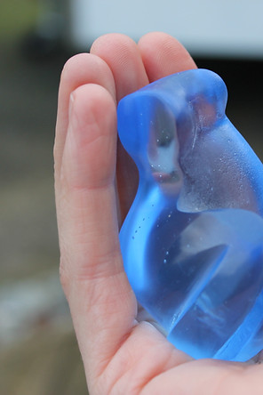 Close up of Jo holding a cast glass sculpture of the Feminine Form in blue
