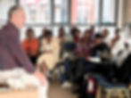 A man teaching a group of attentive students in a classroom.