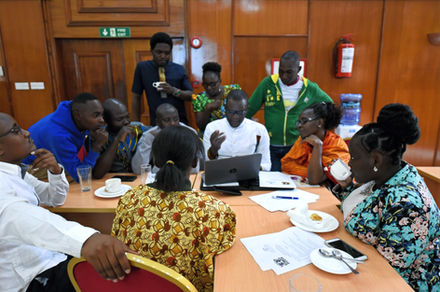 A group gathered around a laptop at a workshop table.