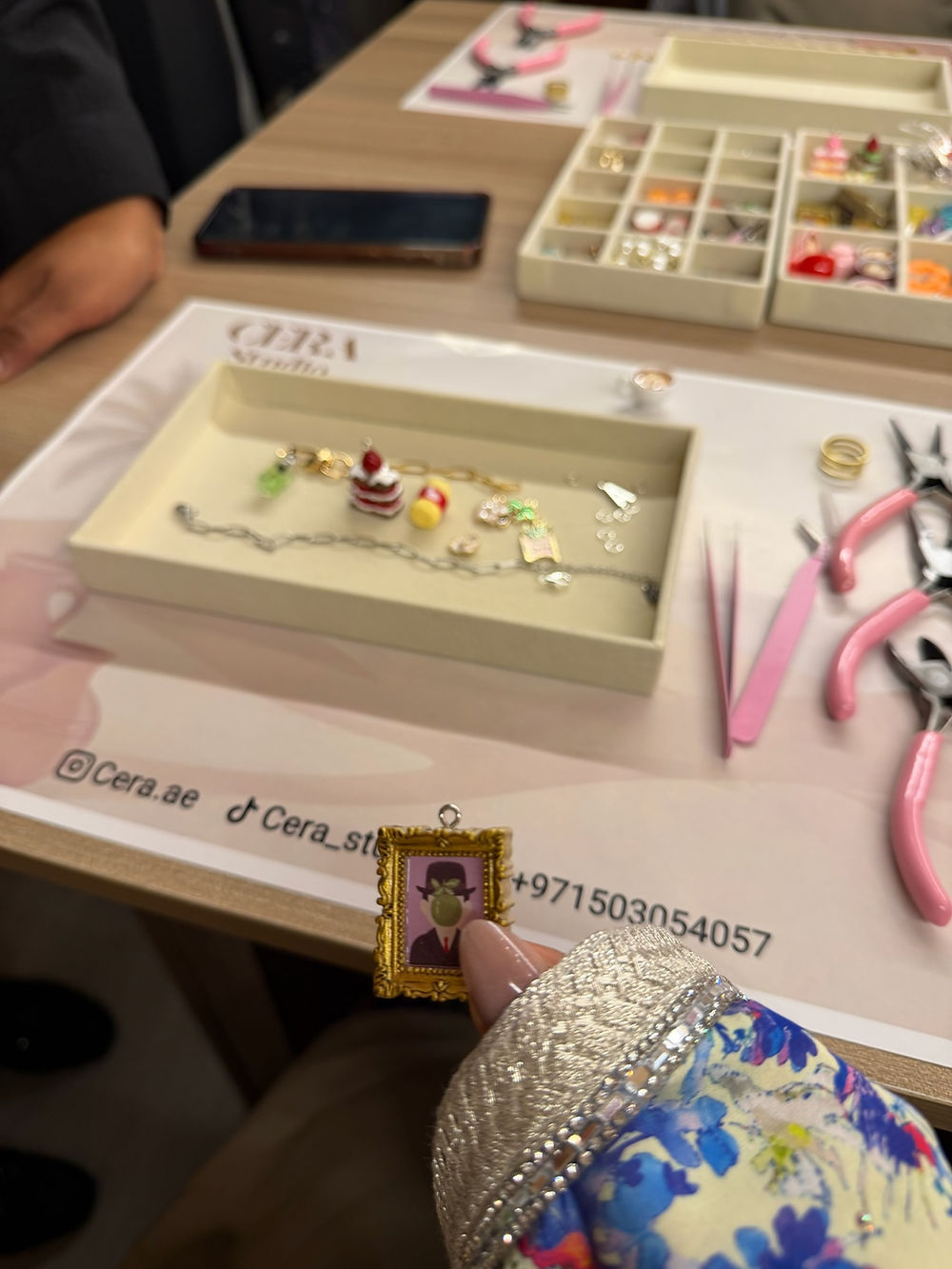 Hand holding tiny framed portrait at a jewelry making workshop