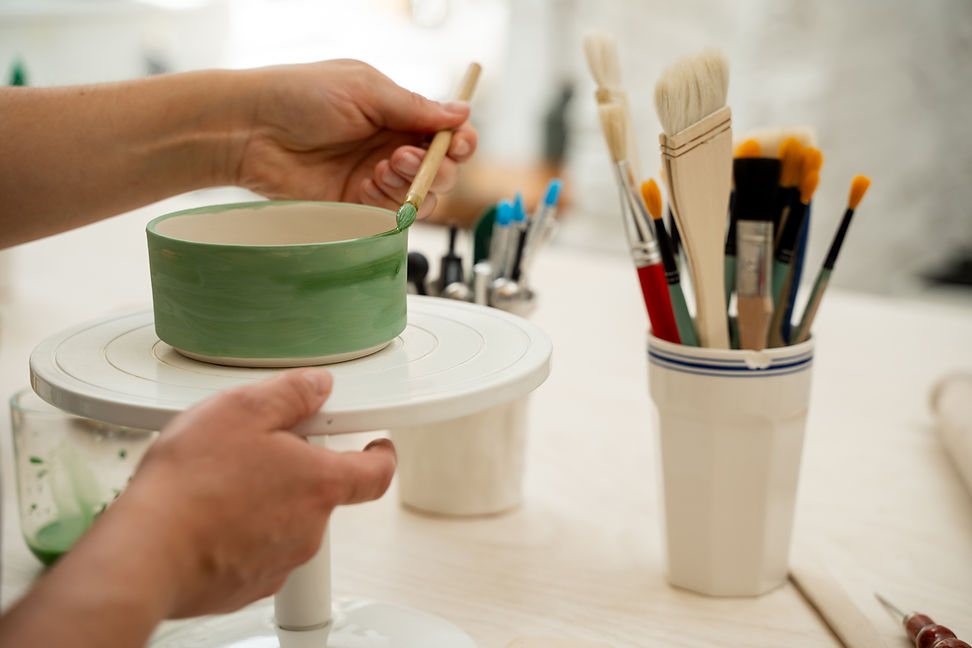 girl-is-decorating-clay-product-with-bright-green-color-using-brush-paint-ceramics-bowl-le