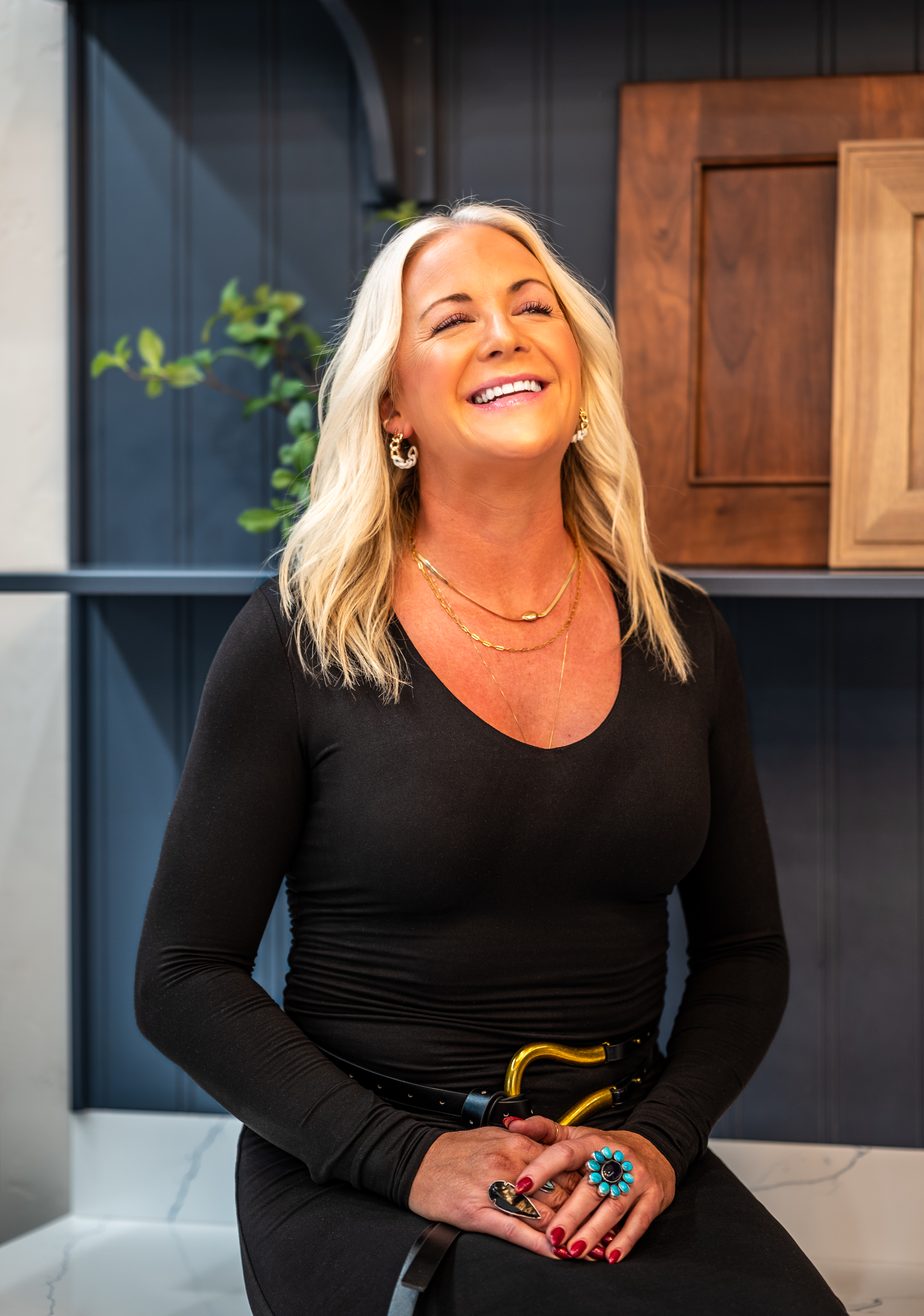 Smiling blonde woman in black top sitting in front of cabinetry samples