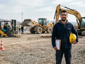 G sınıfı ehliyet için iş makinesi sahasında duran operatör ve farklı makine türleri