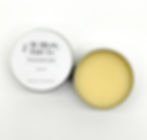 A small round open aluminium tin showing a solid yellow coloured balm