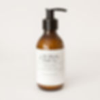 A bottle of hand lotion in a brown glass bottle with a black pump top lid with a white label on the front showing what the name of the hand lotion is on a white background.