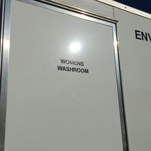 Close-up of a plain white door with 'WOMENS WASHROOM' text