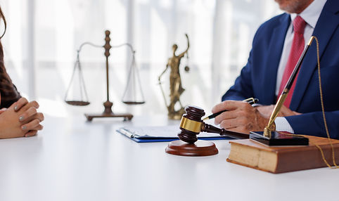 A lawyer in a suit sits across from a client, with a gavel