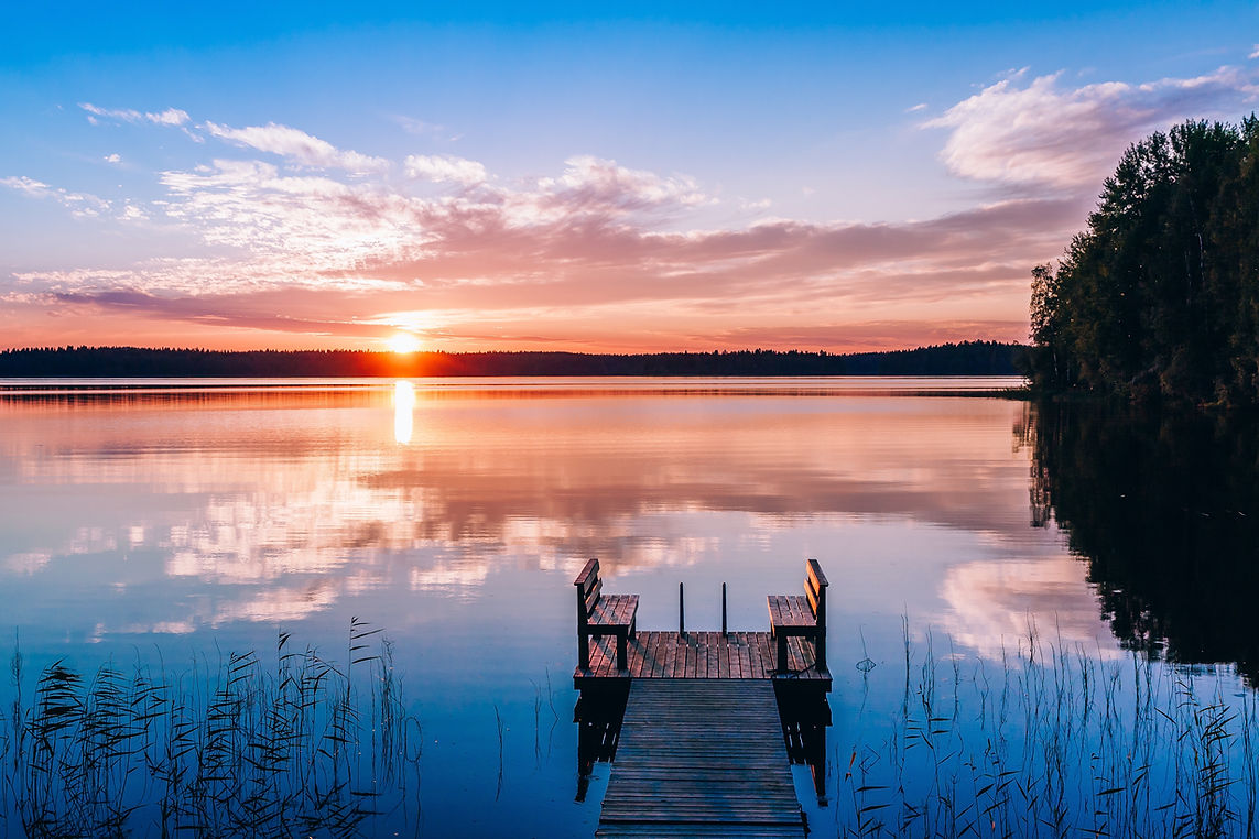 Sunset over a serene lake with a wooden dock in the foreground