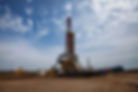 Oil drilling rig under a partly cloudy sky