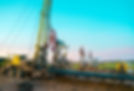 Oil drilling site with multiple pumpjacks and machinery under a bright blue sky
