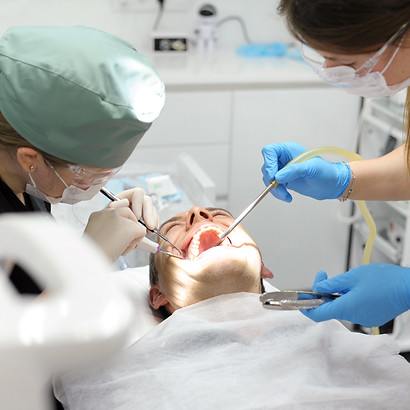 Two dental professionals treat a patient in a clinic