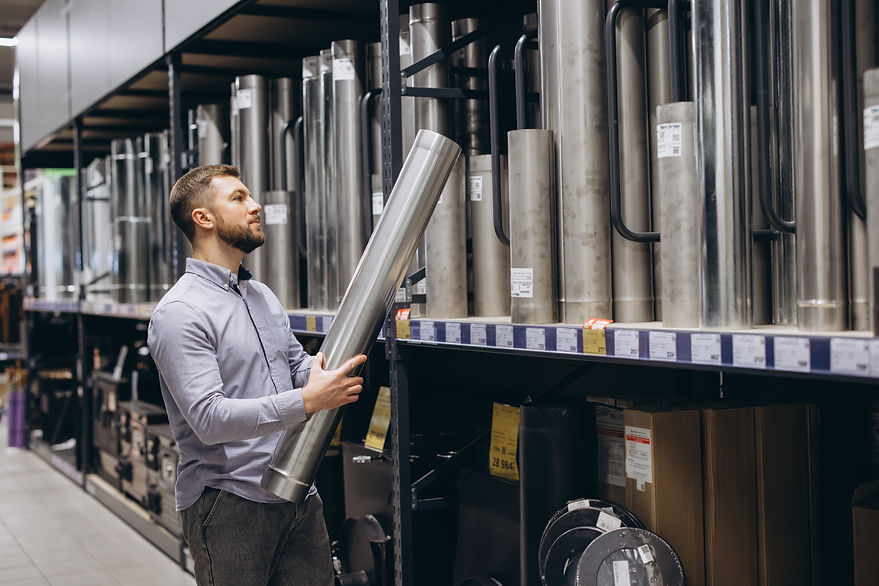 A man in a hardware store inspects a large stainless steel pipe