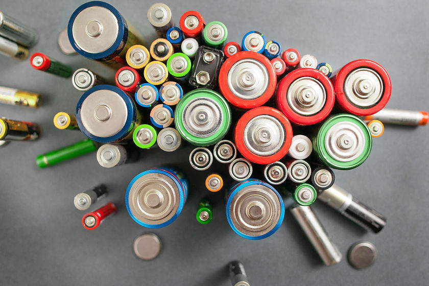A cluster of various batteries viewed from above on a gray background