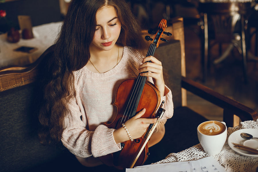 Young woman with long hair holding a violin in a cozy café