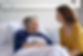 A smiling older woman lies in a hospital bed