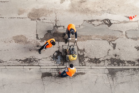 workers in orange vests repairing a cracked road with machinery