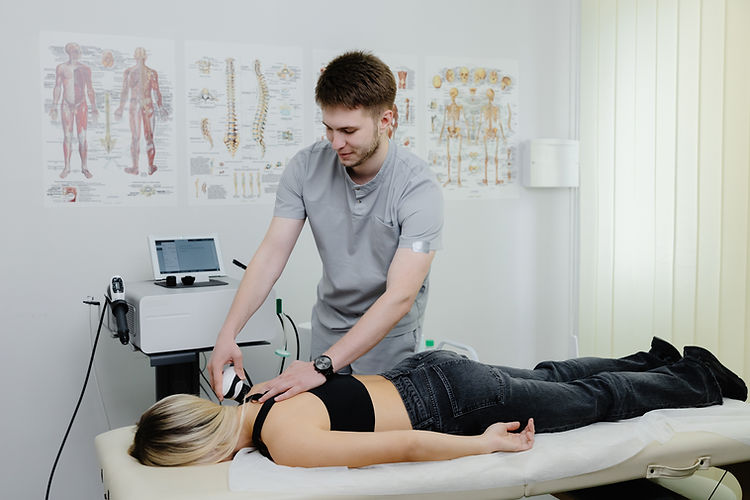 A therapist performs ultrasound therapy on a woman's lower back in a clinic