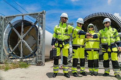 engineers in hard hats and high-visibility jackets inspect a massive piece of industrial equipment