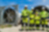 engineers in hard hats and high-visibility jackets inspect a massive piece of industrial equipment