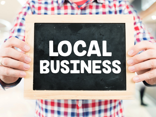 A man is holding a sign displaying the words "local business".