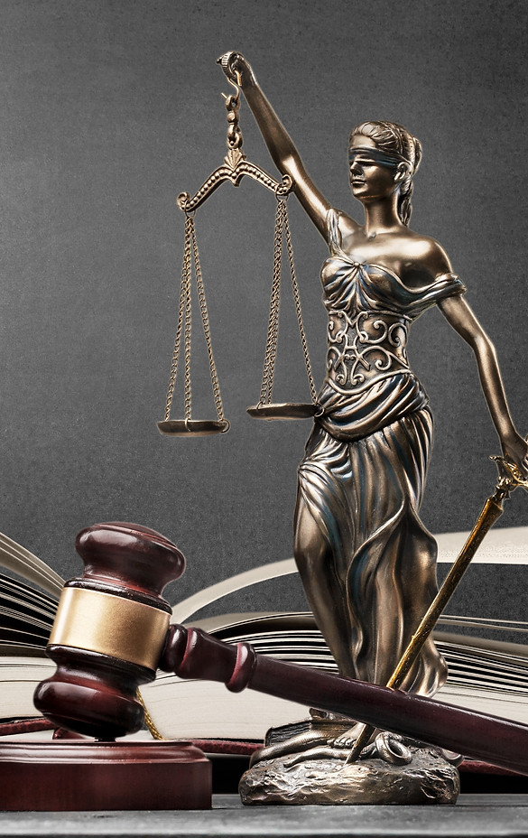 Statue de la Justice et marteau de juge devant un livre de lois ouvert