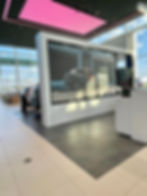 Car showroom interior with a large digital screen displaying a car and person