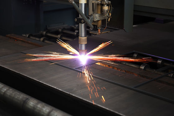 A plasma cutter emits bright sparks and purple light while cutting a steel sheet in an industrial setting