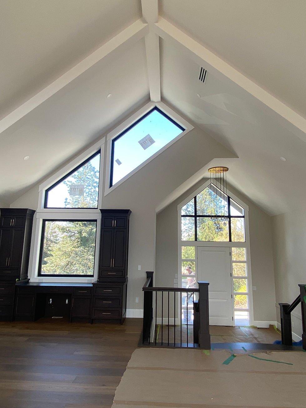 Vaulted room with large triangular windows, dark wood cabinets, and a chandelier