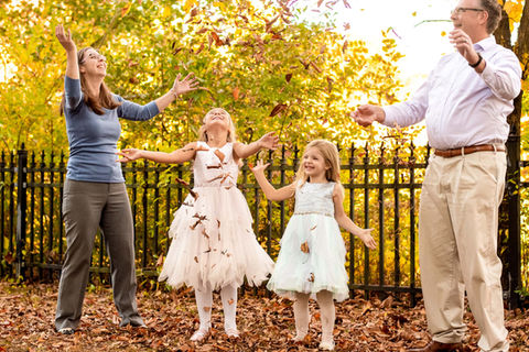Family of four laughing and tossing fall leaves together during an October family photography session at Historic Smithville Park in Eastampton, NJ.