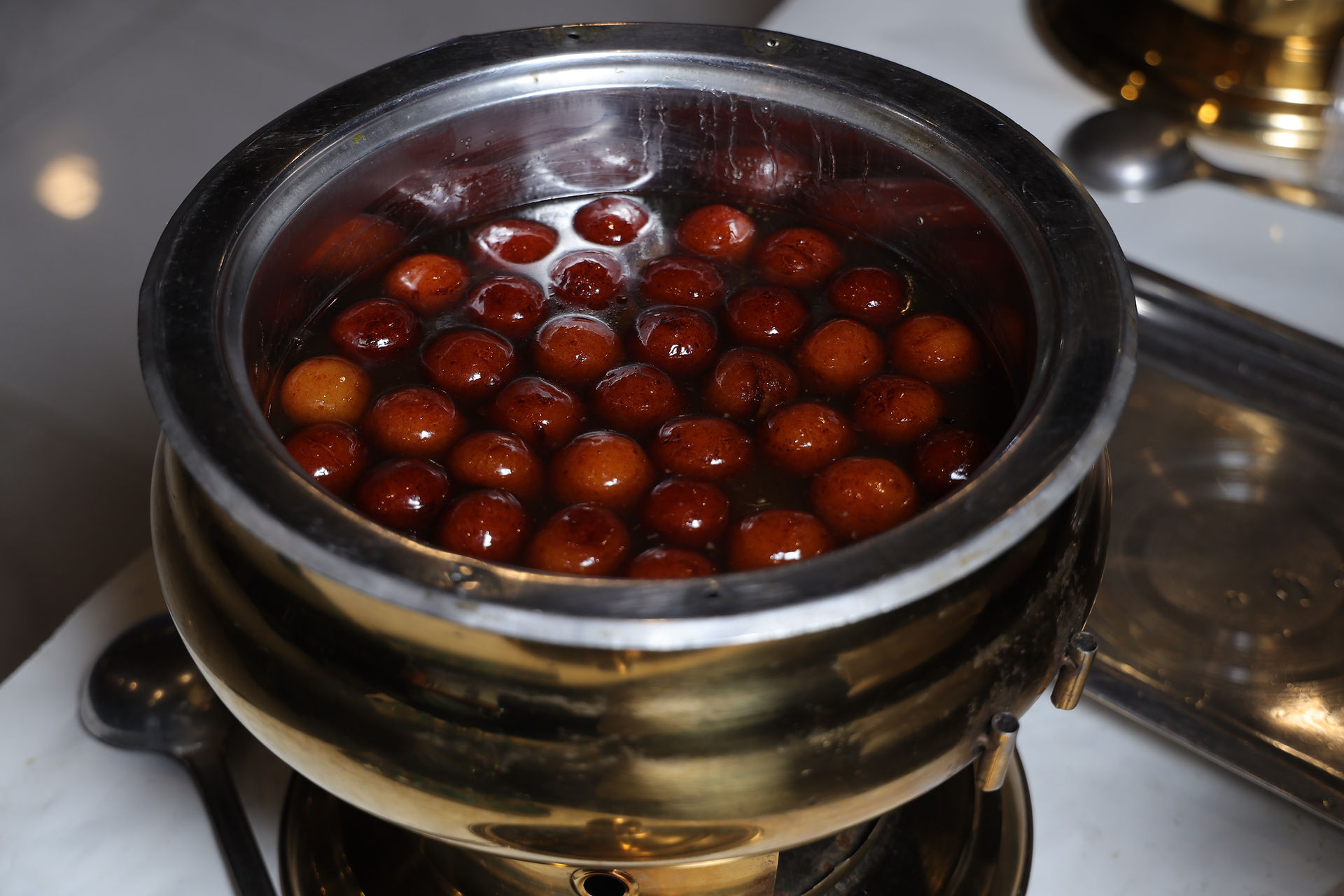 Gulab jamun served in a brass handi