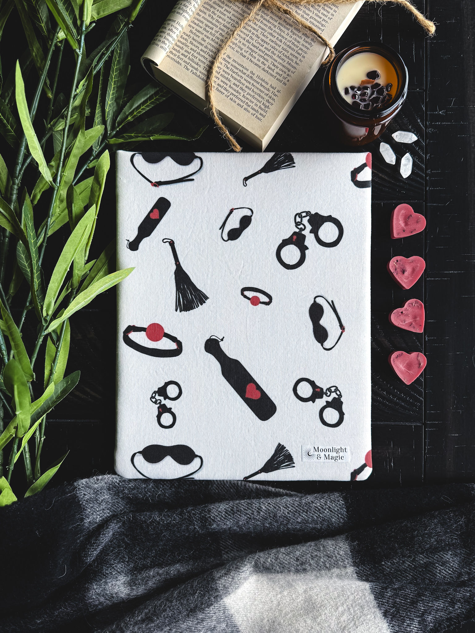 A white book sleeve with different bondage toys in black and red.