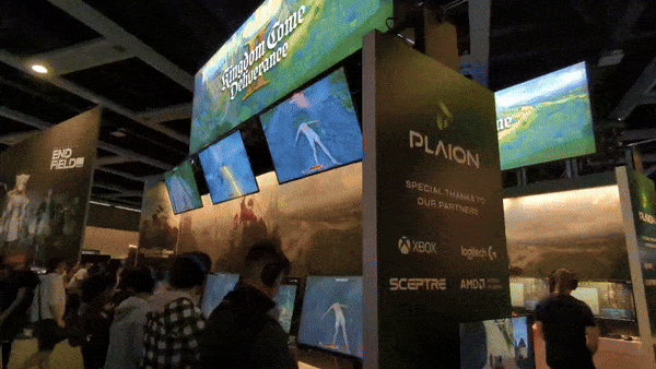 An animated GIF showing PLAION's booth at PAX West 2024. Panning left to right, several stations can be seen running Kingdom Come Deliverance 2, as is also displayed on several banners across the booth. VGG Editor in Chief Nate can be seen masked-up playing on a separate station. A giant tower meant to represent one of the turrets in a castle can be seen in the background.