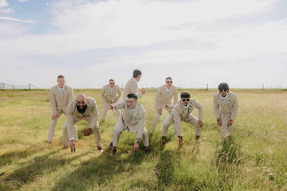 Groomsmen in beige suits pose playfully in a sunny field under a clear sky, exuding a joyful mood on wedding day at wedding venue near New Mexico.