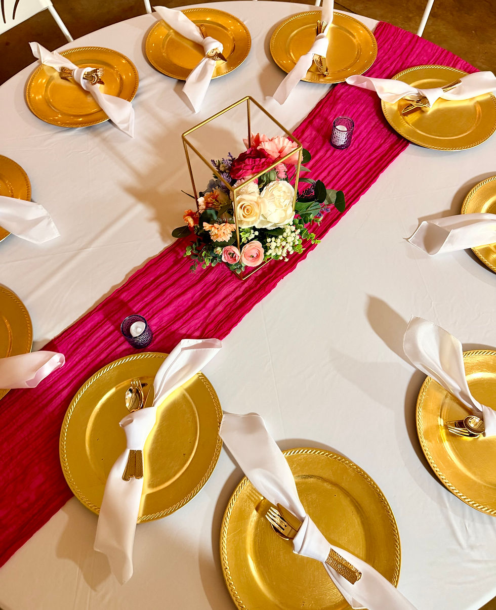 Reception table set with gold charger plates and place settings, with more set tables behind it.