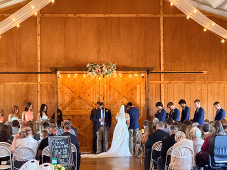 Wedding ceremony inside Amarillo wedding venue near Canyon Texas with rustic barn backdrop, wedding party, and seated guests