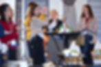 People clapping and smiling around a high table with drinks at a social event. Background shows informational posters and indoor setting.