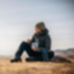 femme occidentale assise sur le sol en Mongolie avec un sachet de nourriture lyophilisé dans les mains