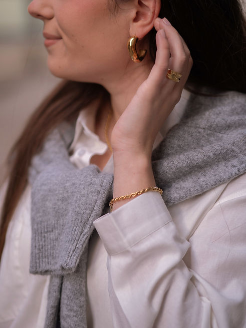 Détails d’un look élégant avec des bijoux dorés et une tenue sobre. Parfait pour un style minimaliste et intemporel, disponible chez Shop Haji.