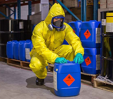Preventative Safety Training - Person in yellow safety jumpsuit with gloves handling hazardous material in blue container with more containers in background