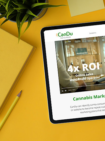 Tablet with CanDu Media's website on screen, with yellow background next to yellow pencil and notebook