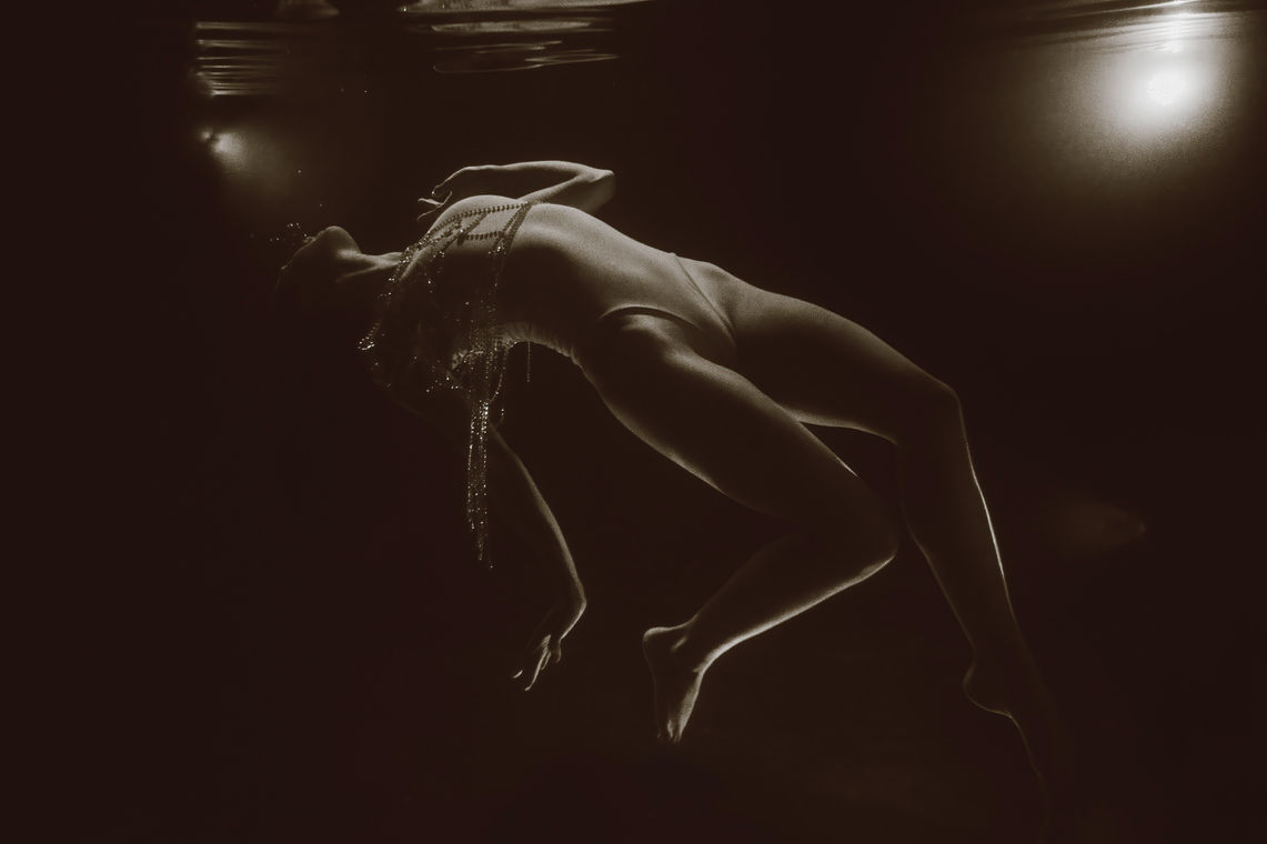 Black and white abstract image of a woman floating chest up with arms and legs hanging in the water. Fine art underwater photographs, Bucks County, PA Lexi Bird Photography